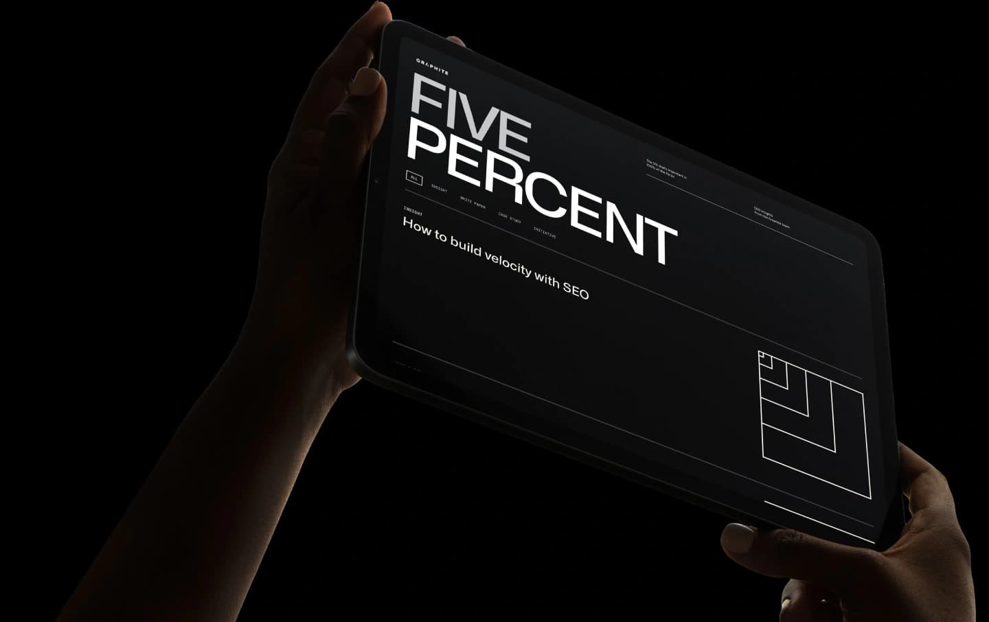 Hand holding a tablet displaying a website design against a dark background